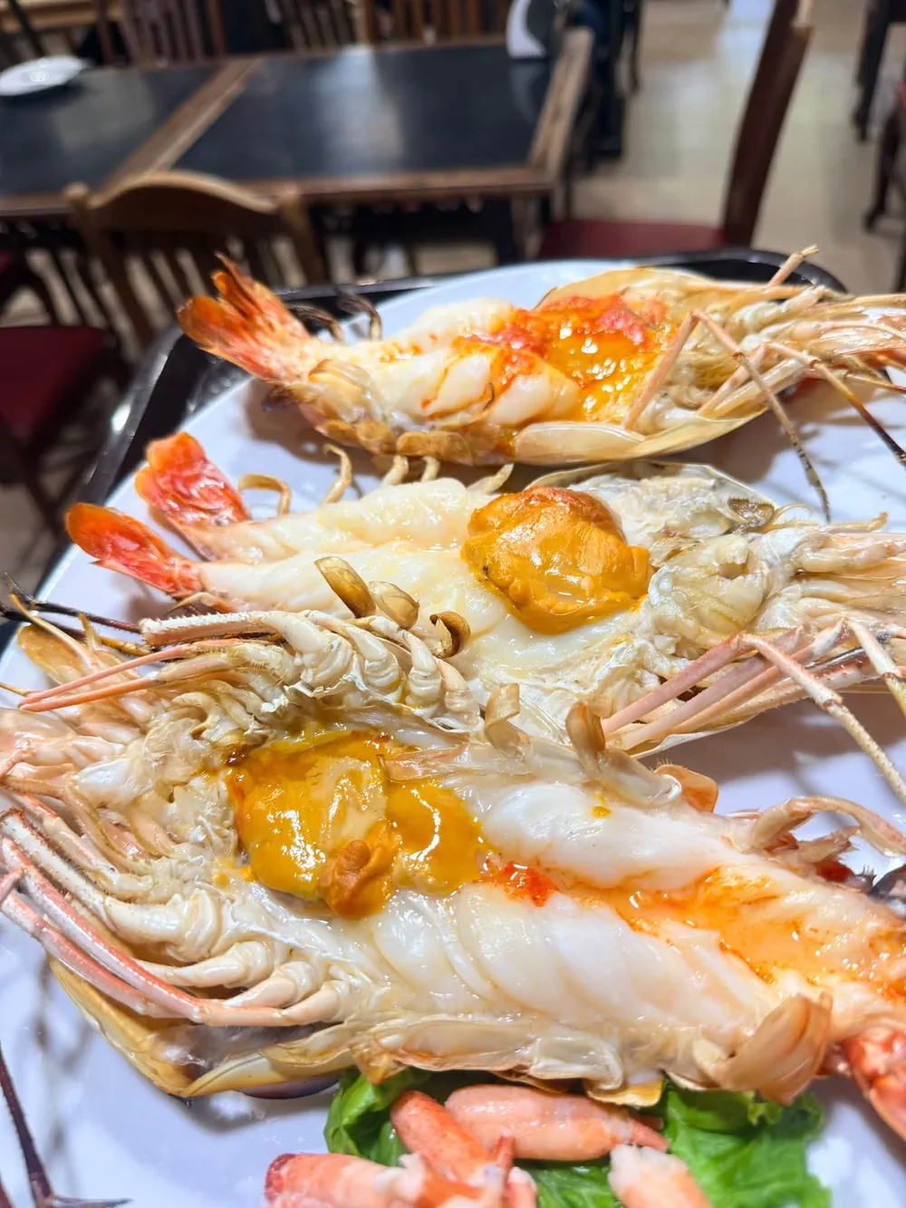 Large river prawns split and grilled, the orange roe visible in the heads.