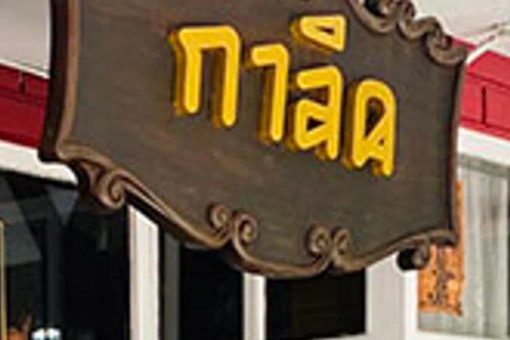 The carved wooden sign above the door, gold Thai lettering reading กาลิค.