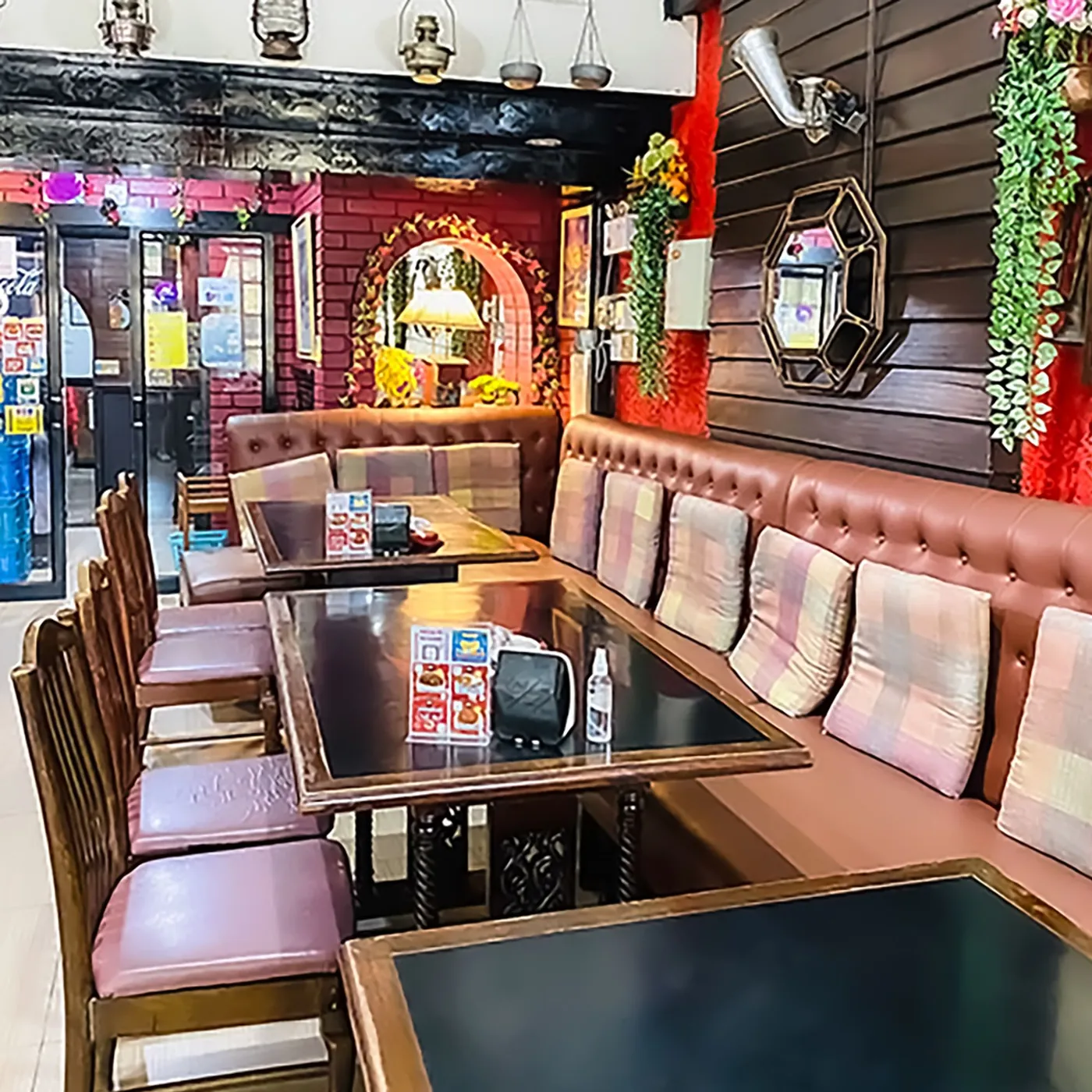 A row of banquette tables inside the restaurant, dark timber against deep red walls.