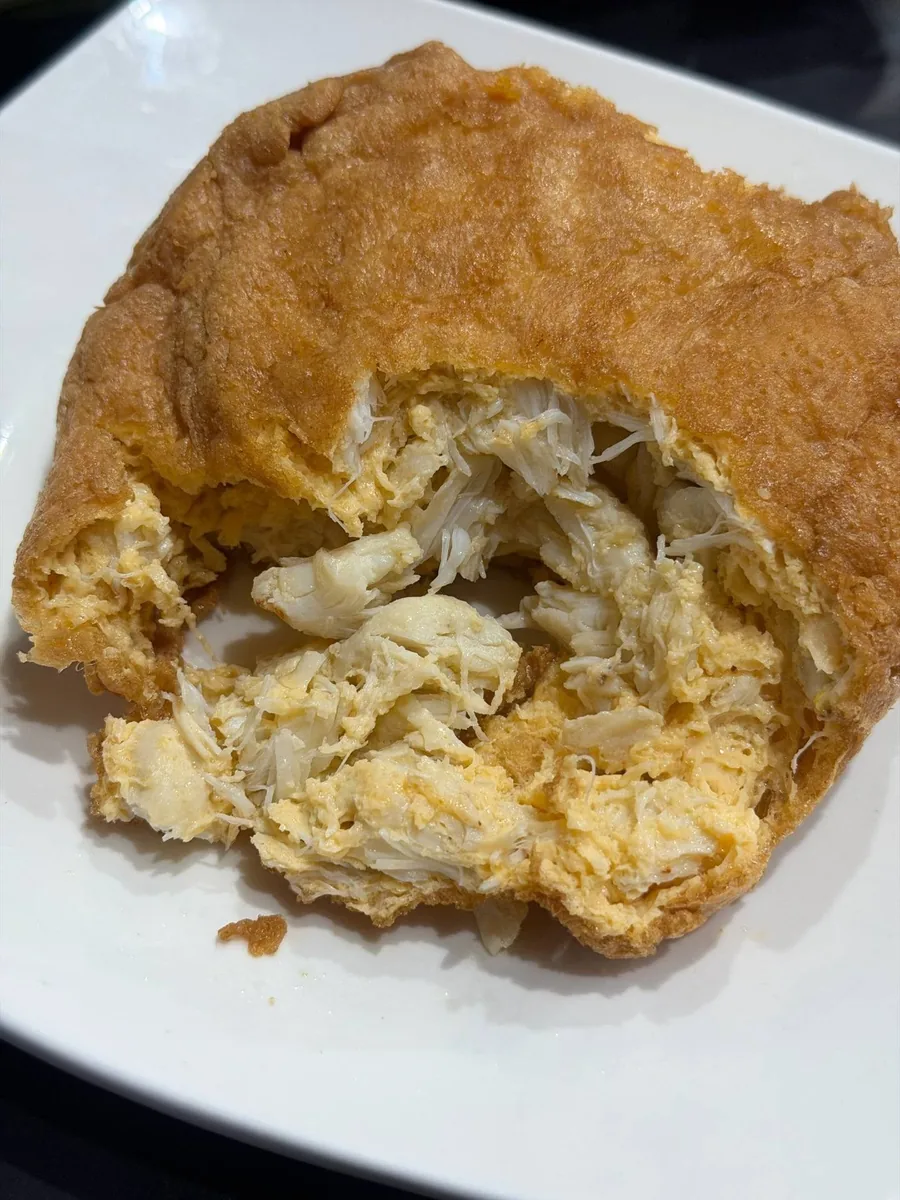 A crab omelette opened up, the golden crust giving way to white crab meat.