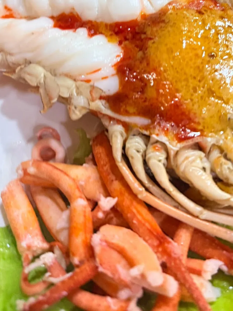 A split river prawn heavy with roe, served alongside crab claws.